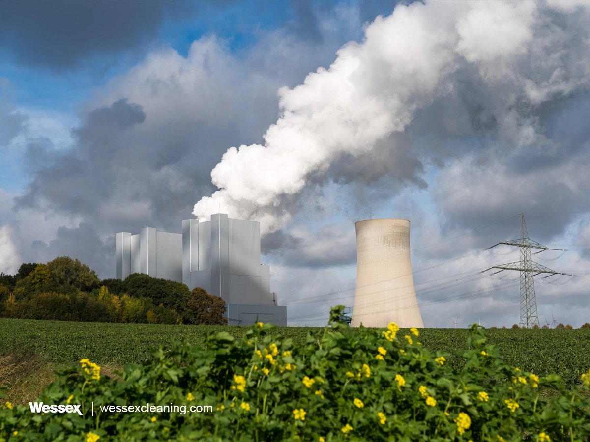 A green grassy landscape with smoke rising from a nuclear power plant in the background, symbolizing the UK’s efforts to achieve Net Zero by 2050 and combat climate change.