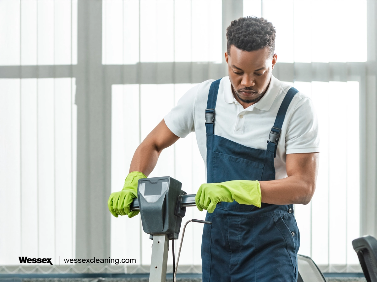 Janitor using a scrubber dryer to clean a floor in a commercial setting.