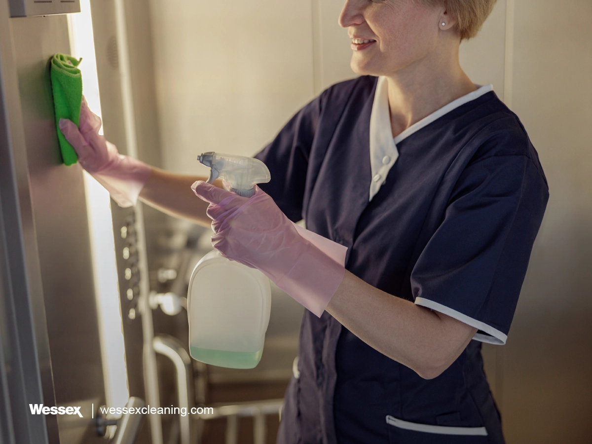 Cleaner using disinfectant in a workplace to maintain hygiene and cleanliness.