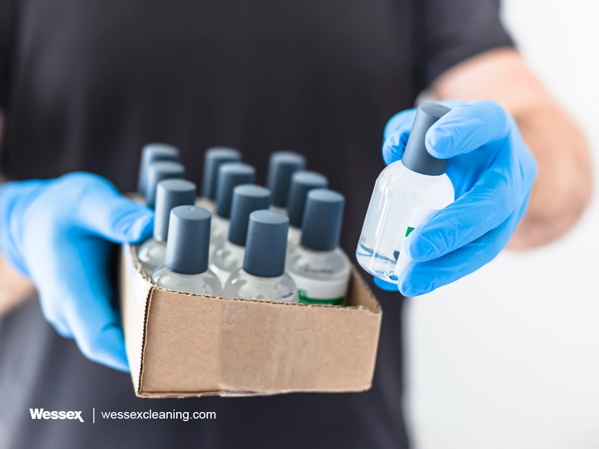 Worker in gloves packing small sanitiser bottles for business use, showcasing the variety of disinfectants and sanitisers.