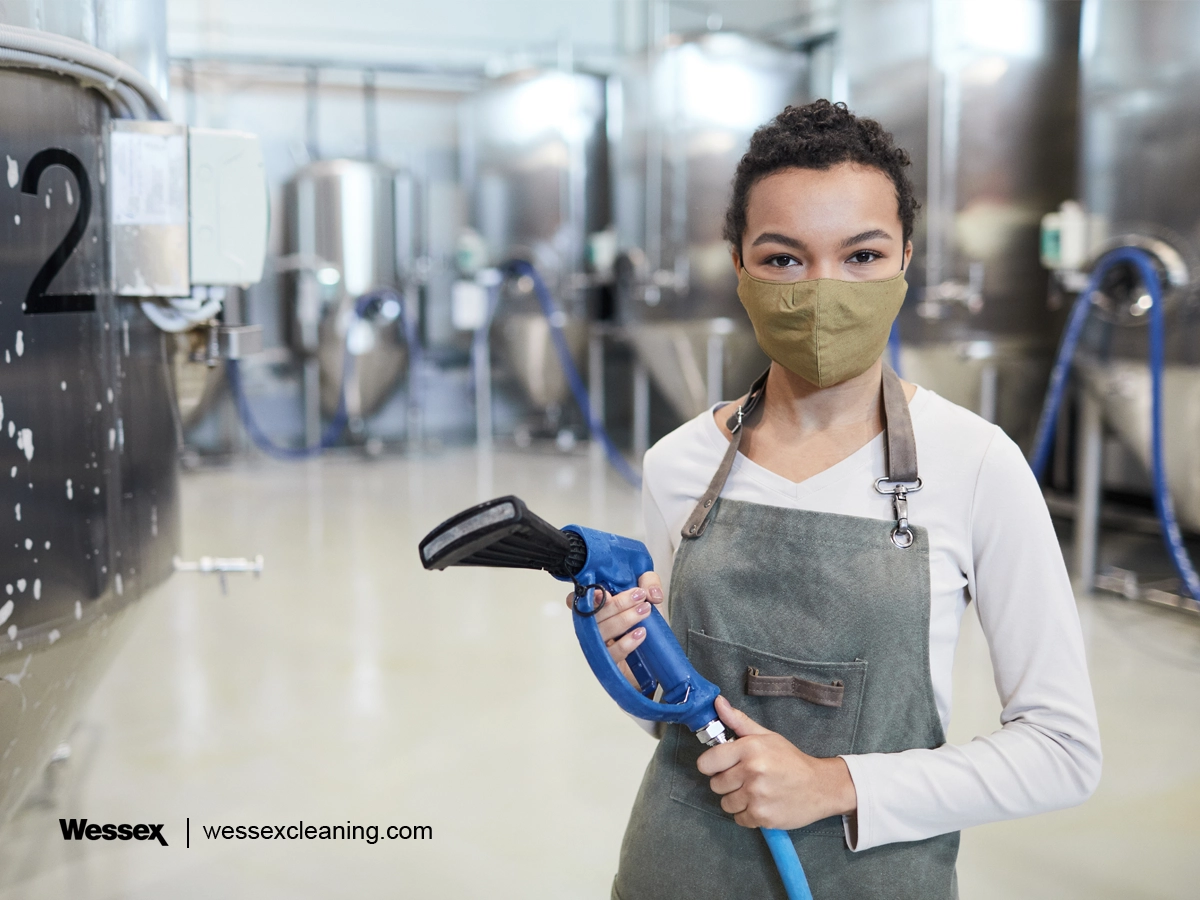 Young woman cleaning in a factory workshop, promoting sustainability and ESG practices in the workplace.