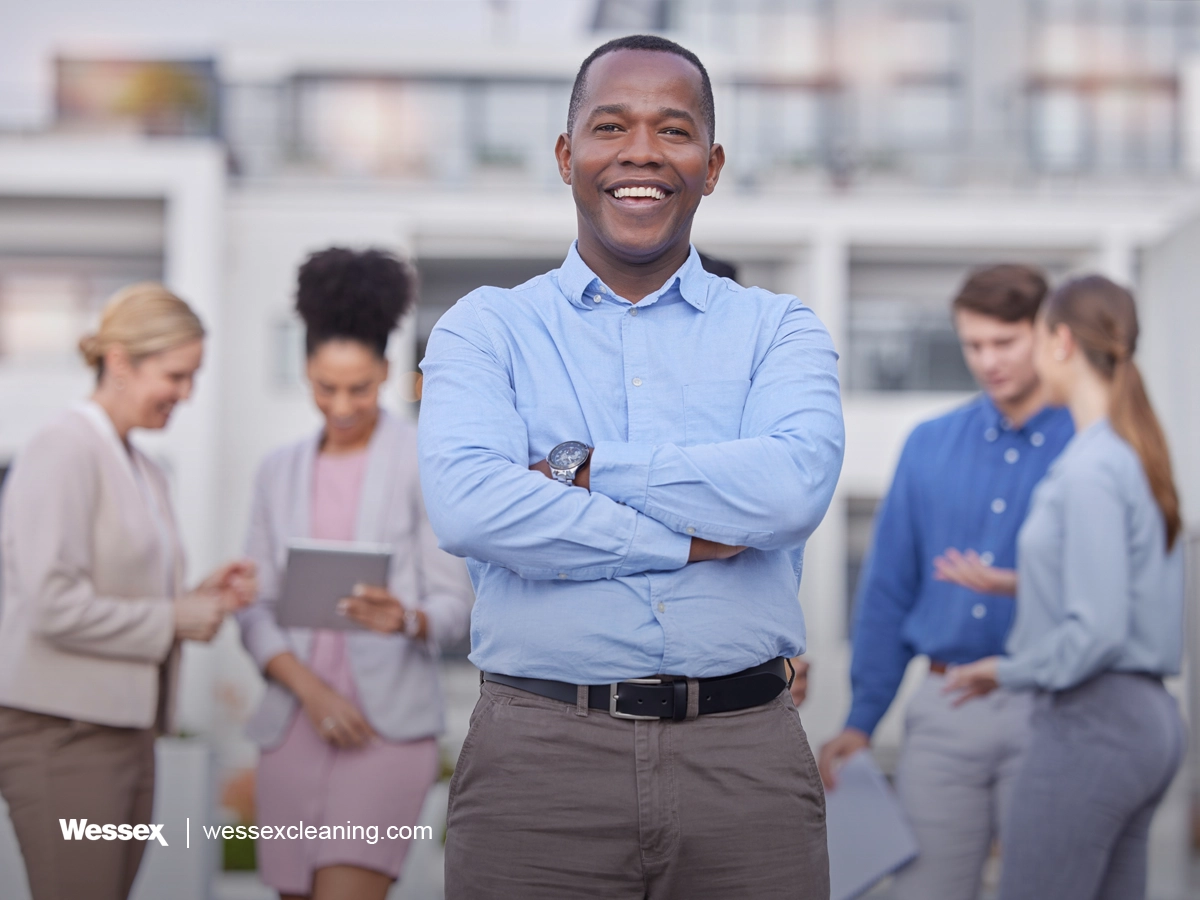 Portrait of a confident black man smiling outside an office, representing leadership and the business benefits of green cleaning.