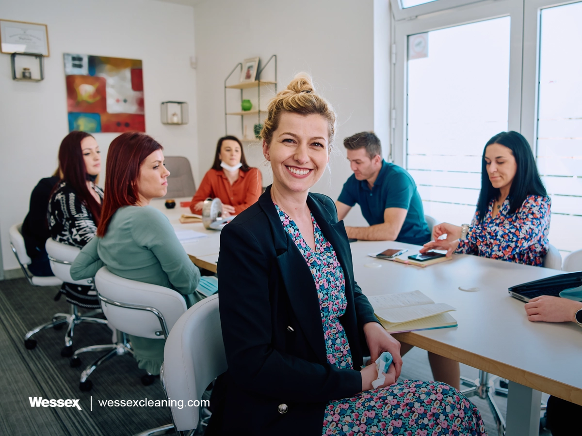 A diverse team of professionals discussing projects in a modern glass office, representing collaboration and a healthy workplace.