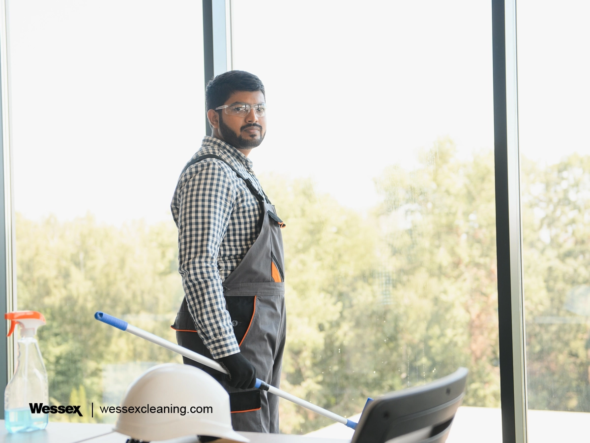 Cheerful male cleaner wiping a window, showing efficient and water-conscious cleaning