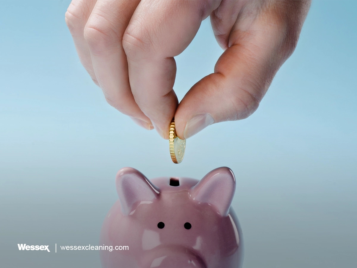 Man putting coin into pink piggy bank on blue background