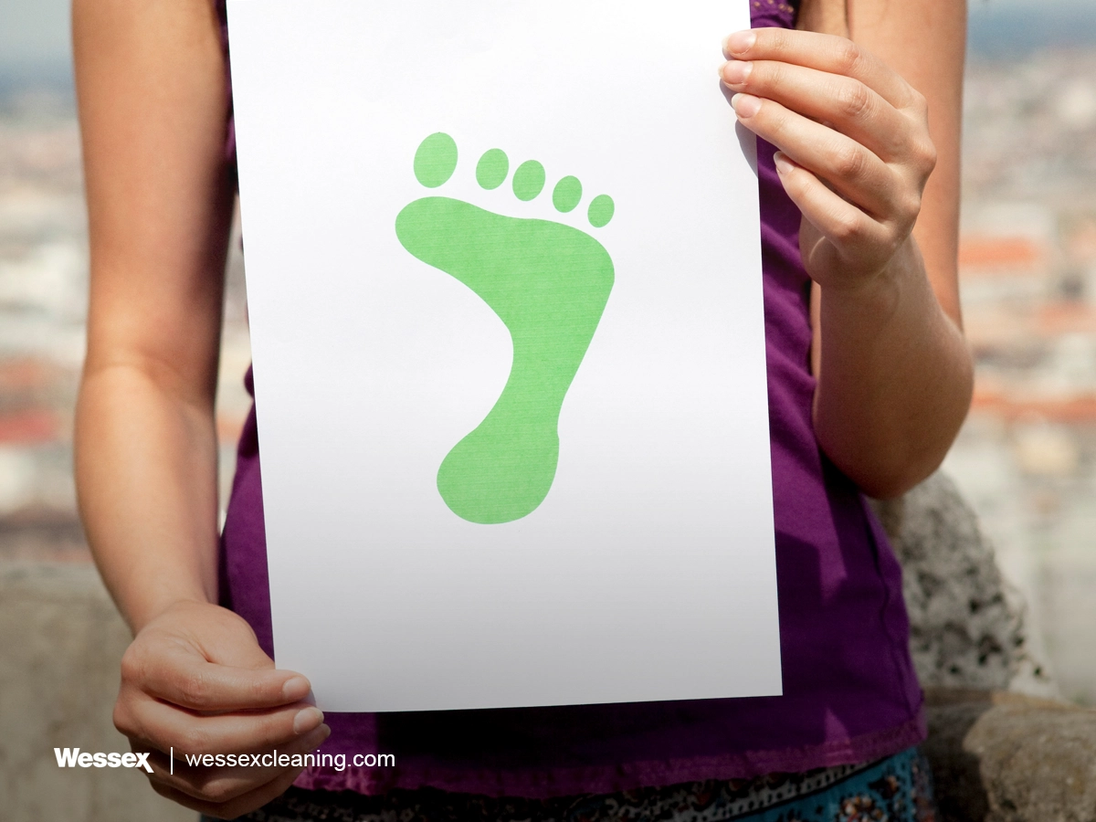 Woman holding a green footprint illustration representing carbon footprint