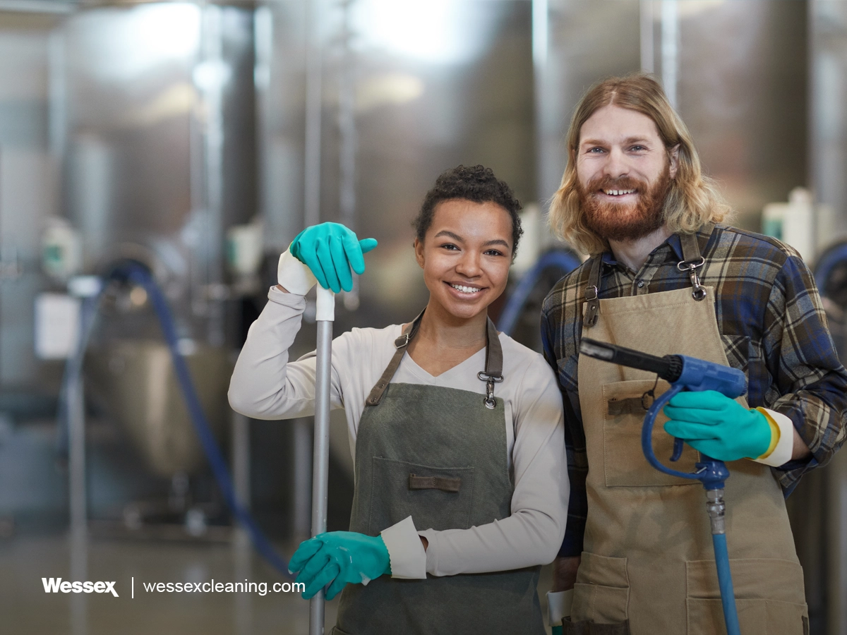 Two cleaning workers smiling at camera in uniform